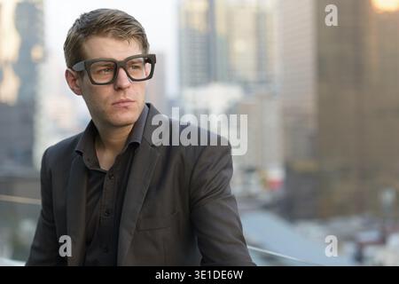 Portrait d'un jeune homme d'affaires élégant en costume contre la vue de la ville Banque D'Images