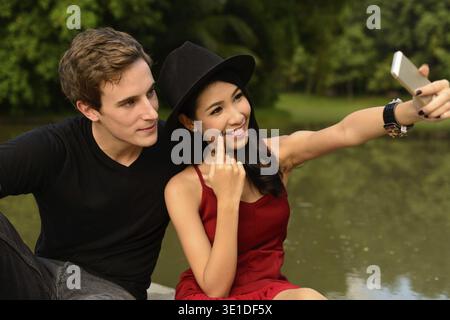 Portrait de jeune homme et jeune femme asiatique comme couple multi ethnique ensemble se relaxant au parc à l'extérieur Banque D'Images