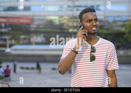 Portrait d'un jeune homme barbu africain aux cheveux afro explorant les rues de la ville en plein air Banque D'Images