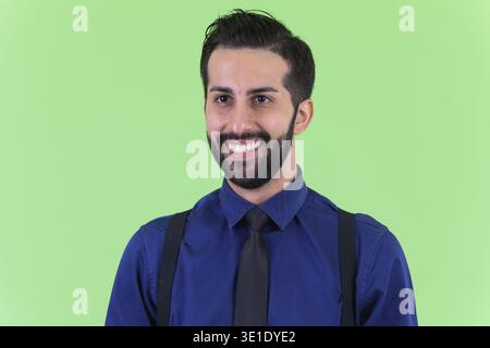 Studio shot du jeune bel homme d'affaires perse barbu sur fond vert Banque D'Images