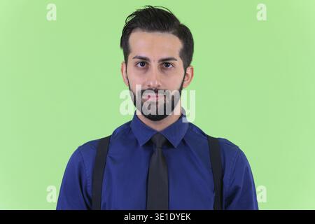 Studio shot du jeune bel homme d'affaires perse barbu sur fond vert Banque D'Images