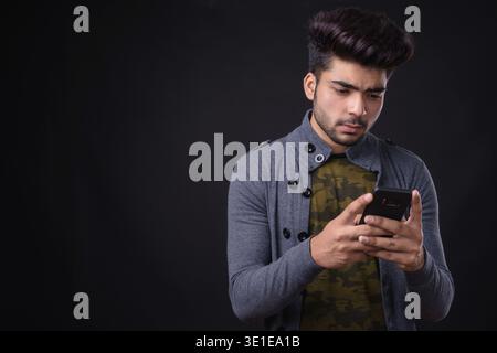 Photo studio d'un jeune homme indien beau sur fond noir Banque D'Images