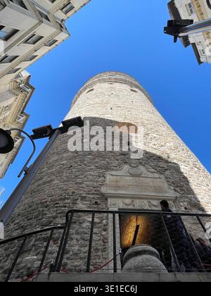 Tour Galata à Istanbul, Turquie, photographiée le 15 mars 2026, vue sous un angle bas avec les bâtiments modernes environnants et le ciel bleu clair. Banque D'Images