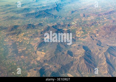 Une vue aérienne montre un paysage de montagnes et de terres agricoles, avec les montagnes en arrière-plan et les terres agricoles au premier plan. Banque D'Images