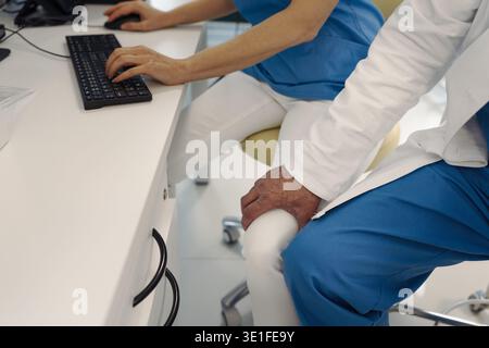 Comportement inapproprié du médecin, tenant l'infirmière par la cuisse. Harcèlement en milieu de travail. Banque D'Images