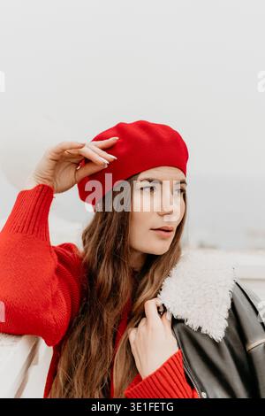 Femme Portrait de mode béret rouge d'une jeune femme en pull rouge et veste en cuir regardant loin avec espace de copie Banque D'Images
