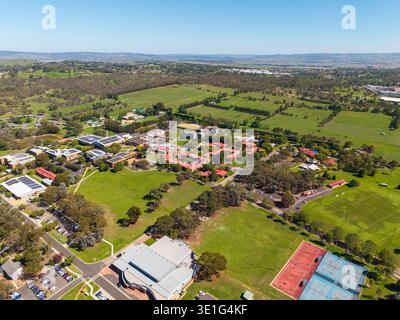 Drone aérien capturant le campus de Bathurst de l'Université Charles Sturt avec des bâtiments, des panneaux solaires, des terrains de sport et des pelouses verdoyantes au milieu d'Austr vallonné Banque D'Images