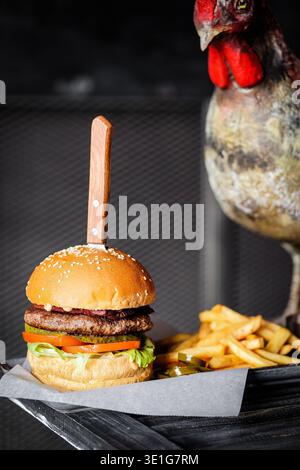 Fête des grignotages pour oiseaux. Scène vivante d'observation des oiseaux sur un hamburger gourmet au sésame avec frites dorées Banque D'Images
