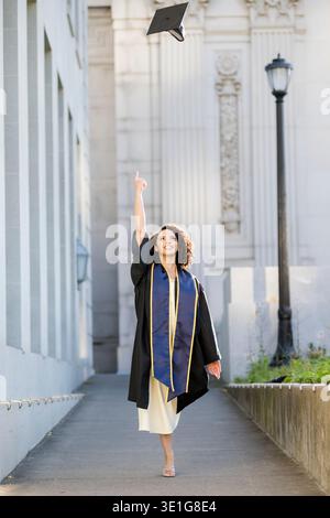 Joyeux diplômé de l'université jetant casquette pour célébrer la réussite Banque D'Images