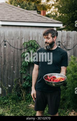 L'homme tient une passoire pleine de fruits et légumes fraîchement récoltés Banque D'Images