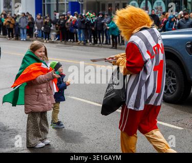 Toronto, Canada 15 mars 2026 : Journée de la St Patricks : la mascotte distribue un dépliant à l'enfant pendant la manifestation Banque D'Images
