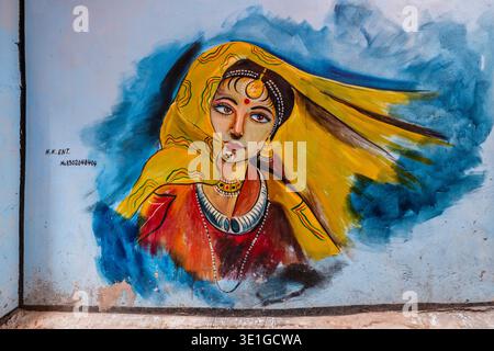 Une murale colorée de rue à Jodhpur représente une femme vêtue d'un voile jaune traditionnel et d'une robe rouge sur un ton bleu. Banque D'Images