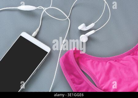 L'invention concerne une composition vue de dessus comprenant un tapis de yoga, des vêtements de sport, une bouteille d'eau et des écouteurs sans fil, symbolisant la préparation à l'exercice à domicile. Banque D'Images