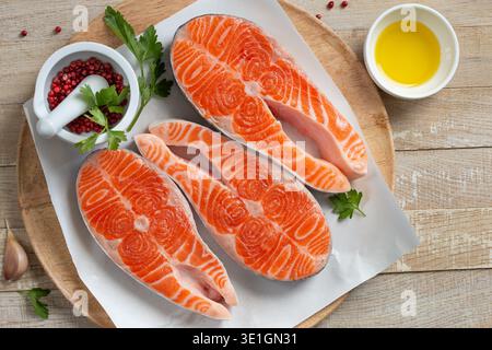 steaks de saumon crus sur plaque blanche, fond en bois, vue de dessus Banque D'Images