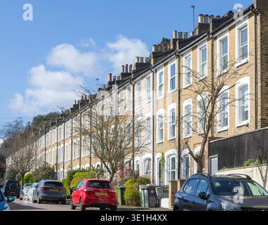 Longue rangée de maisons mitoyennes victoriennes avec des voitures garées sur la rue en face, Mount Ash Road, Lewisham, Londres, SE16, Angleterre, Royaume-Uni construit en 1868 Banque D'Images