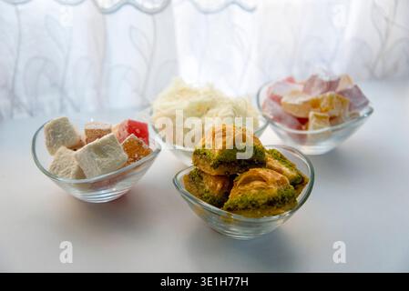 Différents types de bonbons sont disposés dans des bols en verre sur une table. Les friandises comprennent de petites bouchées de baklava, un délice turc, et d'autres confiseries sucrées Banque D'Images