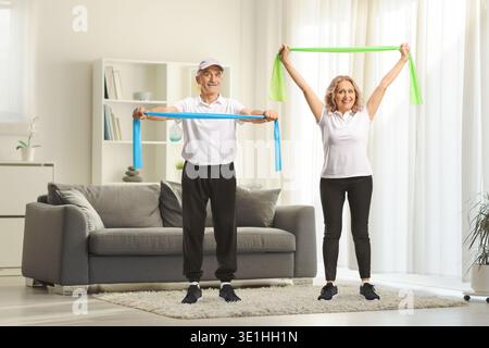 Couple mature exerçant à la maison avec des bandes de résistance Banque D'Images