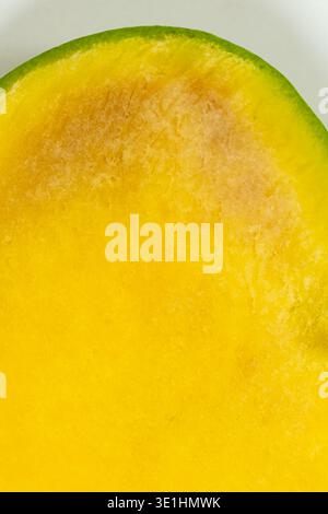 Macro texture de la moitié fraîche de mangue mûre coupée sur fond blanc Banque D'Images