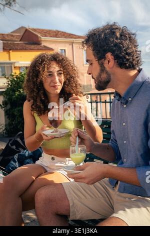 Jeune couple appréciant le granita sicilien traditionnel ensemble dans un café en plein air pendant des vacances d'été dans une ville méditerranéenne. Banque D'Images