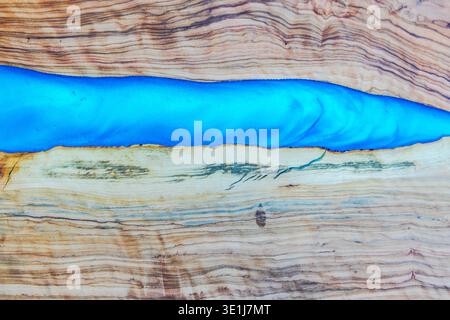 Vue rapprochée de la texture de planche à découper en bois avec motif de rivière en résine bleue. Grèce. Banque D'Images