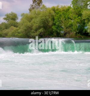 Un paysage naturel époustouflant avec de l'eau de rivière précipitée et un feuillage forestier dense d'été. Cette scène évoque un sentiment de puissance brute et de sérénité, Banque D'Images