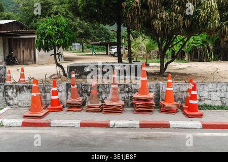 Pile de cônes de circulation orange sur le bord de la route près de la rue du village sur Koh Samui Thaïlande Banque D'Images