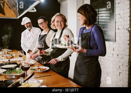 Femmes caucasiennes d'âge moyen appréciant l'expérience de dégustation de repas pendant le cours de cuisine Banque D'Images