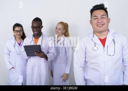 Portrait of happy Young Asian man médecin avec divers groupes ethniques de médecins de sourire et de penser lors de la lecture sur l'ensemble du presse-papiers Banque D'Images