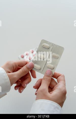 Gros plan de la main femelle prenant Blister Pack alors que les pilules en vrac se trouvent sur la table - médecine et pharmacie concept photo verticale avec espace pour le texte Banque D'Images