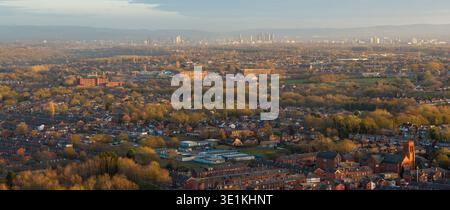 Image aérienne regardant vers le sud-est de Bolton vers les gratte-ciels lointains de Manchester et Salford, encadrés par la verdure luxuriante banlieue. Banque D'Images