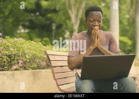 Portrait d'un jeune bel homme africain se relaxant au parc dans la ville en plein air Banque D'Images