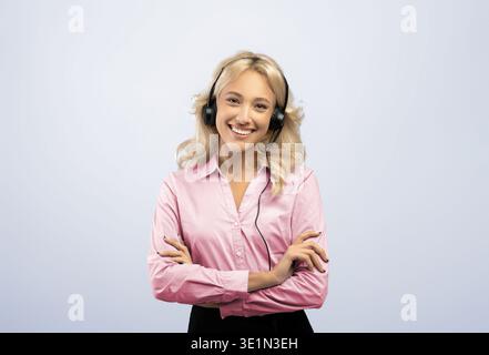 Femme sourit en portant un casque dans un arrière-plan ordinaire pendant les heures de travail dans un bureau occupé Banque D'Images