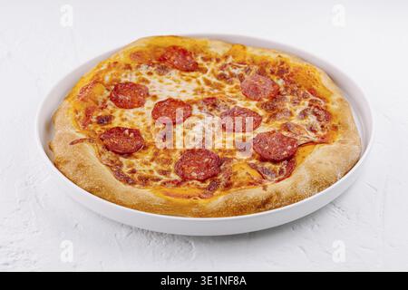 Délicieuse pizza pepperoni classique servie sur une assiette en céramique sur fond blanc Banque D'Images