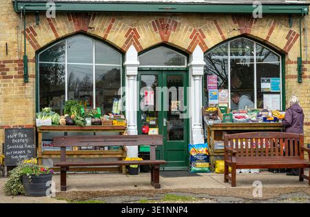 Magasin de village traditionnel à Freshwater sur l'île de wight, magasin du coin à l'ancienne avec femme choisissant des légumes exposés à l'extérieur. Banque D'Images