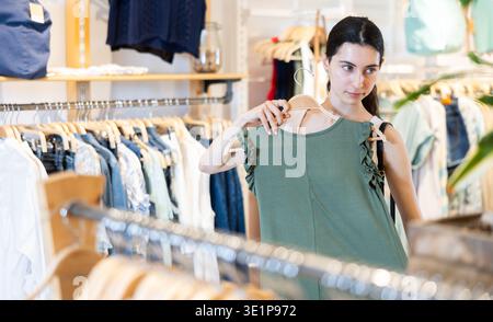La cliente fille choisit un chemisier dans le magasin de marque Banque D'Images