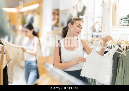 La cliente choisit un chemisier singulet dans le magasin de marque Banque D'Images