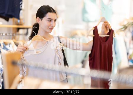 La cliente fille choisit un chemisier dans le magasin de marque Banque D'Images