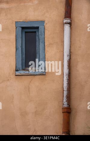 Fenêtre en bois bleu et tuyau rouillé sur le mur extérieur de l'ancien bâtiment maison de style adobe à Santa Fe Nouveau Mexique vertical voyage tourisme grunge toile de fond Banque D'Images