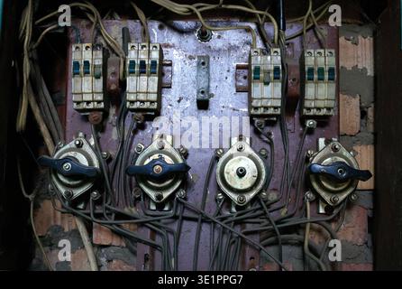 Vieux panneau électrique, interrupteurs vintage et fils enchevêtrés. Gros plan boîte à fusibles industrielle obsolète avec des composants vieillissants montés sur un mur de briques, illustr Banque D'Images