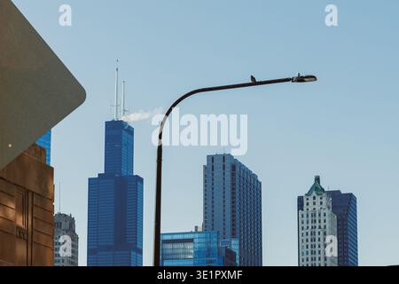 De grands bâtiments s'élèvent dans le ciel avec un lampadaire au premier plan. Le réglage montre un ciel bleu clair sans nuages. Un panneau est partiellement visible Banque D'Images