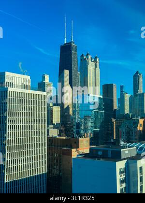La scène montre une ligne d'horizon de Chicago avec de nombreux bâtiments hauts. Certains sont en verre et en acier. Le ciel est clair et lumineux. La lumière du soleil se reflète donc Banque D'Images