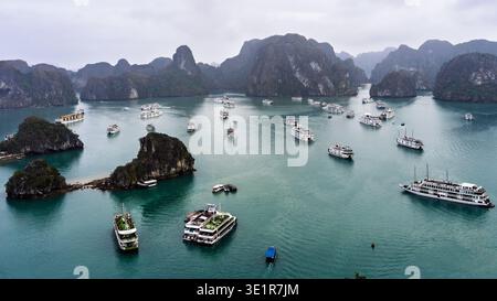 Vue aérienne de la baie d'Ha long, Vietnam, avec des îles calcaires et des bateaux de croisière touristiques Banque D'Images