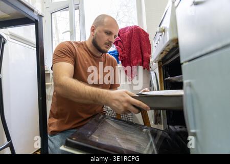 Homme mettant la plaque de cuisson dans le four Banque D'Images