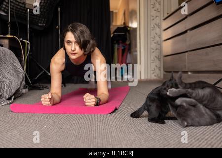 Femme tenant une pose de planche sur un tapis de yoga Banque D'Images