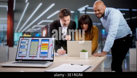 L'équipe diverse collabore à la conception d'applications, en développant des interfaces conviviales. Web Developer étudie l'interface utilisateur sur Un ordinateur portable Banque D'Images