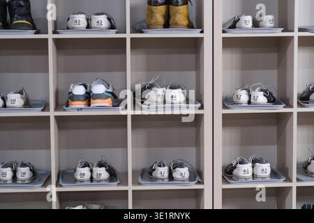 Unité de rangement organisée pour chaussures affichant différentes paires de chaussures et bottes de sport avec des étiquettes numérotées sur les étagères pour une identification facile Banque D'Images