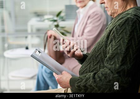 Homme senior utilisant smartphone en attendant dans le cabinet médical Banque D'Images
