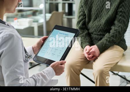 Médecin féminin montrant les résultats de test sanguin à l'homme adulte Banque D'Images