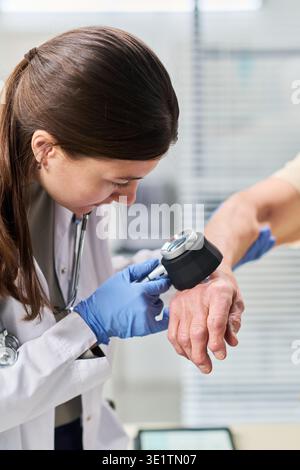 Jeune médecin féminin examinant la main du patient masculin senior Banque D'Images