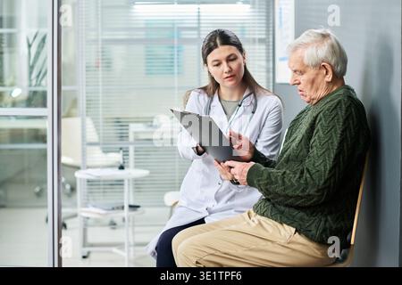 Médecin féminin expliquant les résultats médicaux à l'homme senior Banque D'Images